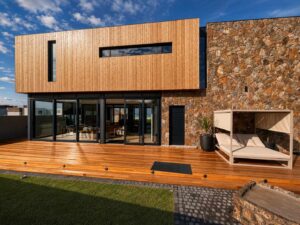 Rear garden elevation of House 671 with timber cladding, stonework and full-height glazing