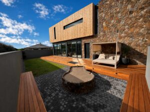 Sheltered rear courtyard at House 671 with a timber deck, stone walls and circular fire pit