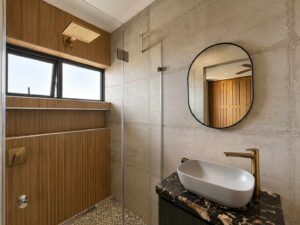 Walk-in shower and vanity at House 671 with stone-look tiles and timber cabinetry