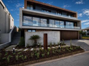 Angled street view of House 671 in Stilbaai showing the glazed upper floor, entrance and landscaped frontage