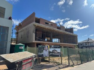 Front view of House 671 during construction, showing concrete structure, brickwork and site fencing